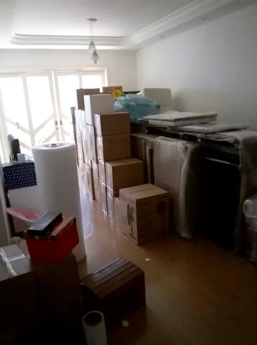 Sala com caixas de mudança, rolo de plástico bolha e móveis embalados pela Japan Mudanças